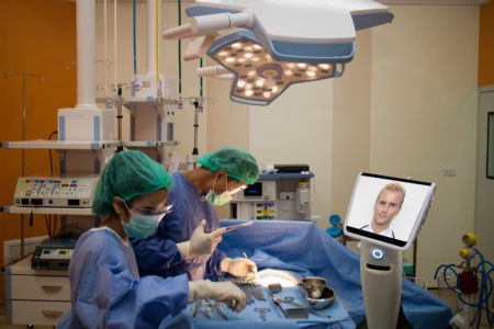 bigstock--205919893 doctor surgery patient in operating room in hospital and talk consult with specialist doctor by telepresence robot during emergency. robot(artificial intelligence) technology for betterefficiency